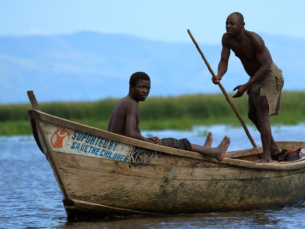 Fishermen poling a wooden boat on Lake Albert